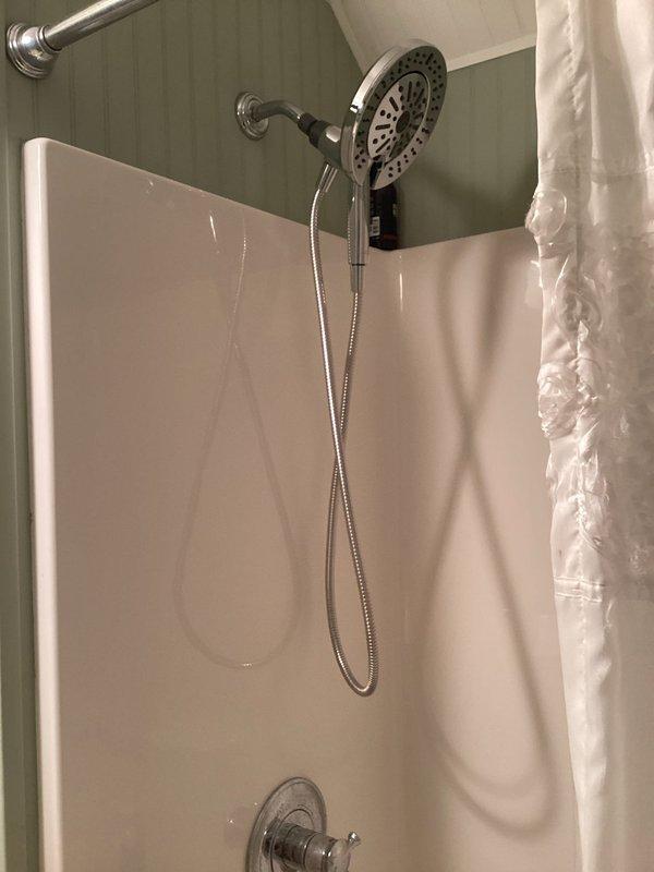 Installed client-supplied dual-flush toilet with elongated bowl design in bathroom with beadboard paneling. Diagnosed and resolved shower diverter malfunction that was preventing water flow to tub spout, restoring proper function to dual-head shower system with handheld attachment. All fixtures tested and confirmed operational upon completion.