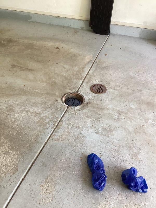 Replaced two deteriorated metal floor drains in garage due to one drain being broken and the other showing significant rust and corrosion. Removed old rusted drain covers and installed new perforated metal grate assemblies to restore proper drainage function and prevent safety hazards from compromised drain components.