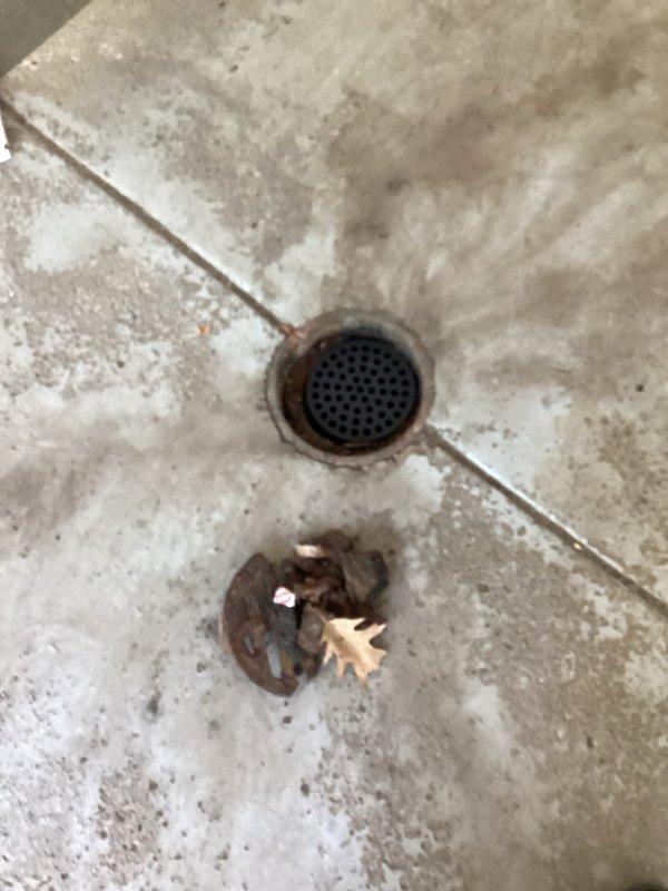 Replaced two deteriorated metal floor drains in garage due to one drain being broken and the other showing significant rust and corrosion. Removed old rusted drain covers and installed new perforated metal grate assemblies to restore proper drainage function and prevent safety hazards from compromised drain components.