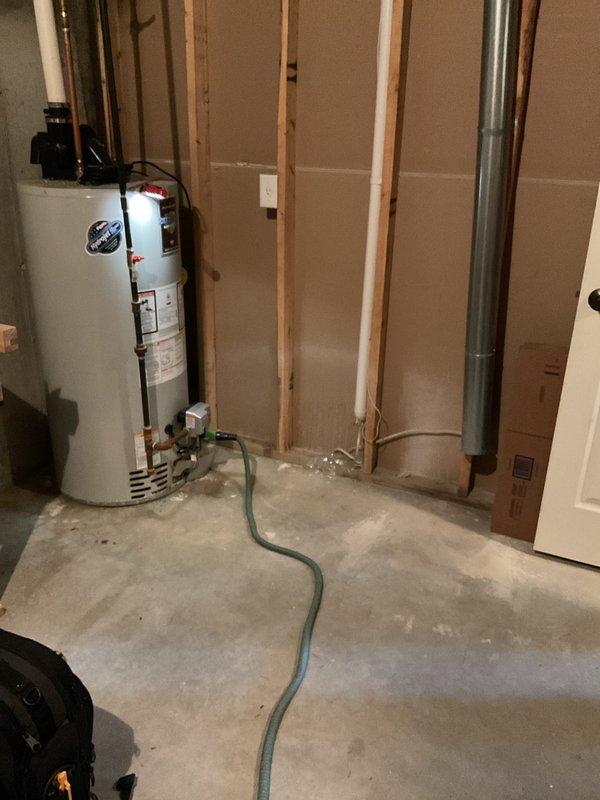 Completed water heater replacement estimate for a single-family residence with a 15-year-old existing unit located in an unfinished basement utility area. Assessed current water heater condition, documented existing plumbing connections including copper supply lines and drainage configuration, and photographed installation area showing accessible wooden stud framing and adequate clearances for replacement. Provided homeowner with replacement options and specifications for new water heater installation.