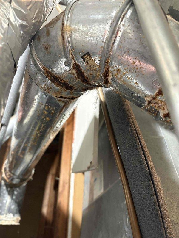 Responded to water leak investigation following home inspector's report of possible water intrusion in ductwork near furnace. Upon inspection, found significant rust and corrosion on galvanized metal ductwork at junction points and seams near furnace connection, consistent with previous moisture exposure. Confirmed prior chimney leak had been repaired several months ago. Documented extensive rust patterns on duct elbows and connector pieces with photographic evidence. Verified heating system currently operational with 17-year-old furnace and 30-year-old AC unit. No active leaking observed at time of inspection, and homeowner reported no current issues with system performance in other areas.
