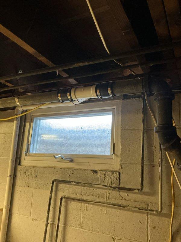 Responded to kitchen drain running slow due to suspected improper venting and incorrect plumbing configuration. Upon inspection, identified horizontal drain line in basement with inadequate pitch and corroded cast iron piping with deteriorated joints contributing to drainage issues. Documented existing plumbing system showing improperly installed drain line secured to floor joists and aging cast iron stack with visible rust and corrosion at connection points affecting flow capacity.