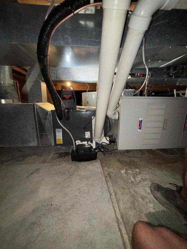 Completed full air conditioning system replacement including outdoor condenser unit and indoor air handler. Installed new condensing unit on existing concrete pad with proper refrigerant line connections, electrical conduit, and PVC drainage piping. Indoor air handler positioned in basement mechanical room with black flexible ductwork integration, vertical PVC condensate drain lines, and all necessary electrical connections completed to manufacturer specifications.