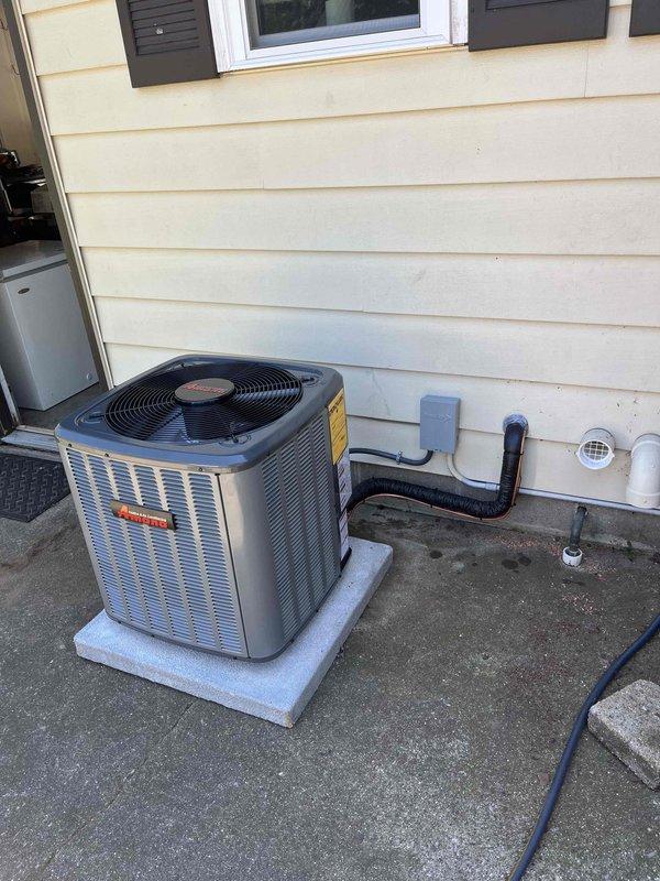 Completed full air conditioning system replacement including outdoor condenser unit and indoor air handler. Installed new condensing unit on existing concrete pad with proper refrigerant line connections, electrical conduit, and PVC drainage piping. Indoor air handler positioned in basement mechanical room with black flexible ductwork integration, vertical PVC condensate drain lines, and all necessary electrical connections completed to manufacturer specifications.
