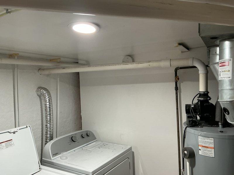 Completed comprehensive rental inspection of water heater and laundry appliances in utility room. Documented condition of white top-loading washing machine, dryer, and cylindrical water heater with associated plumbing connections, flexible ductwork, and PVC piping systems. Photographed all mechanical components, fixtures, and utility infrastructure to provide detailed visual record of property condition for rental assessment purposes.