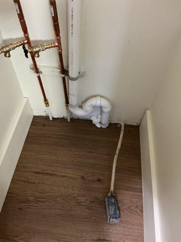 Inspected washer and dryer hookups in utility area to verify proper installation of copper water supply lines with shutoff valves and white PVC drain configuration prior to appliance delivery. Installed new bathroom sink vanity and backlit mirror in bathroom with turquoise walls, confirming GFCI outlet functionality for mirror electrical connection. All plumbing connections and electrical components verified as code-compliant and operational in this century-old home.