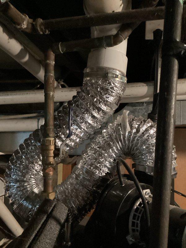 Responded to service call for 12-year-old EnergiAir system experiencing hissing noise and inadequate cooling. Upon inspection, examined both indoor air handler unit in basement/utility area and outdoor condensing unit. Indoor unit showed complex ductwork configuration with flexible aluminum ducting connected to PVC components via metal clamps, with visible dark piping potentially indicating refrigerant lines with foam insulation. Outdoor condensing unit appeared structurally sound with intact louvered panels and fan grille assembly, positioned on concrete pad with electrical disconnect properly installed. Diagnosed refrigerant leak as source of hissing noise causing reduced cooling capacity. System evaluation revealed age-related wear on refrigerant lines and connections contributing to performance issues. Documented equipment condition through photographic evidence for service records.