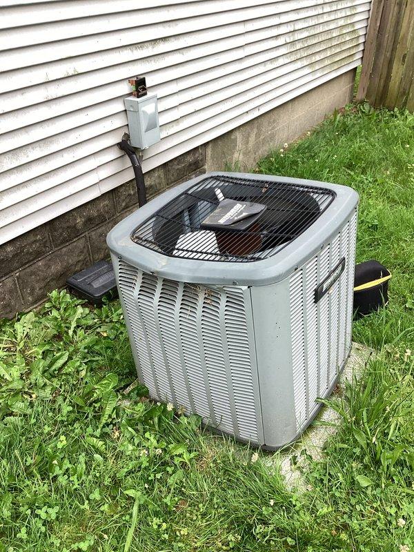 Responded to service call for 12-year-old EnergiAir system experiencing hissing noise and inadequate cooling. Upon inspection, examined both indoor air handler unit in basement/utility area and outdoor condensing unit. Indoor unit showed complex ductwork configuration with flexible aluminum ducting connected to PVC components via metal clamps, with visible dark piping potentially indicating refrigerant lines with foam insulation. Outdoor condensing unit appeared structurally sound with intact louvered panels and fan grille assembly, positioned on concrete pad with electrical disconnect properly installed. Diagnosed refrigerant leak as source of hissing noise causing reduced cooling capacity. System evaluation revealed age-related wear on refrigerant lines and connections contributing to performance issues. Documented equipment condition through photographic evidence for service records.