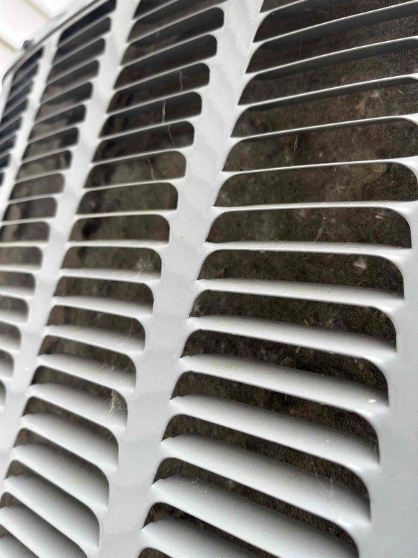 Completed annual cooling system tune-up and inspection under active EnergiAir warranty coverage. Performed comprehensive evaluation of air conditioning equipment, including examination of ventilation components and heat exchanger surfaces. Documented significant accumulation of dust, dirt, and possible microbial growth on air return grille surfaces, particularly concentrated on interior slat surfaces where contamination has built up over time. Inspected HVAC unit components including white-painted metal panels, horizontal louvers, and ventilation grilles, noting normal operational wear on exterior surfaces. Photographed conditions for warranty documentation and service records. System operational at time of service completion.