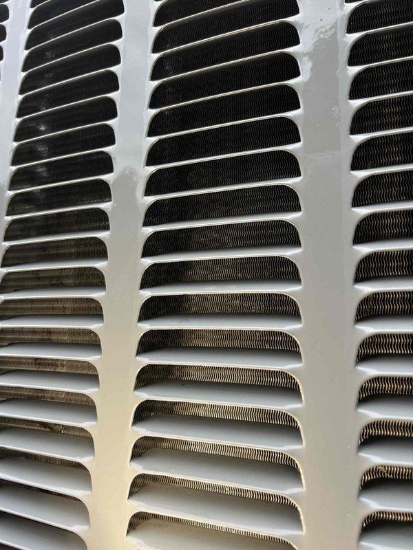 Completed annual cooling system tune-up and inspection under active EnergiAir warranty coverage. Performed comprehensive evaluation of air conditioning equipment, including examination of ventilation components and heat exchanger surfaces. Documented significant accumulation of dust, dirt, and possible microbial growth on air return grille surfaces, particularly concentrated on interior slat surfaces where contamination has built up over time. Inspected HVAC unit components including white-painted metal panels, horizontal louvers, and ventilation grilles, noting normal operational wear on exterior surfaces. Photographed conditions for warranty documentation and service records. System operational at time of service completion.