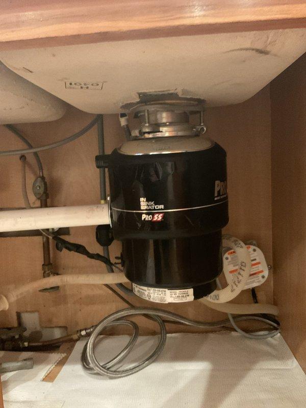 Responded to non-functional garbage disposal at kitchen sink in 20-year-old home. Upon arrival, inspected InSinkErator Pro SS disposal unit mounted beneath double-basin stainless steel sink. Tested unit for power and mechanical function, identified issue preventing operation. Reset disposal using bottom-mounted reset button and verified electrical connection at power outlet in cabinet. Cleared minor obstruction from disposal chamber and confirmed grinding mechanism operated freely. Tested unit under running water to verify full functionality restored. Disposal now operating normally with proper drainage in both sink basins.