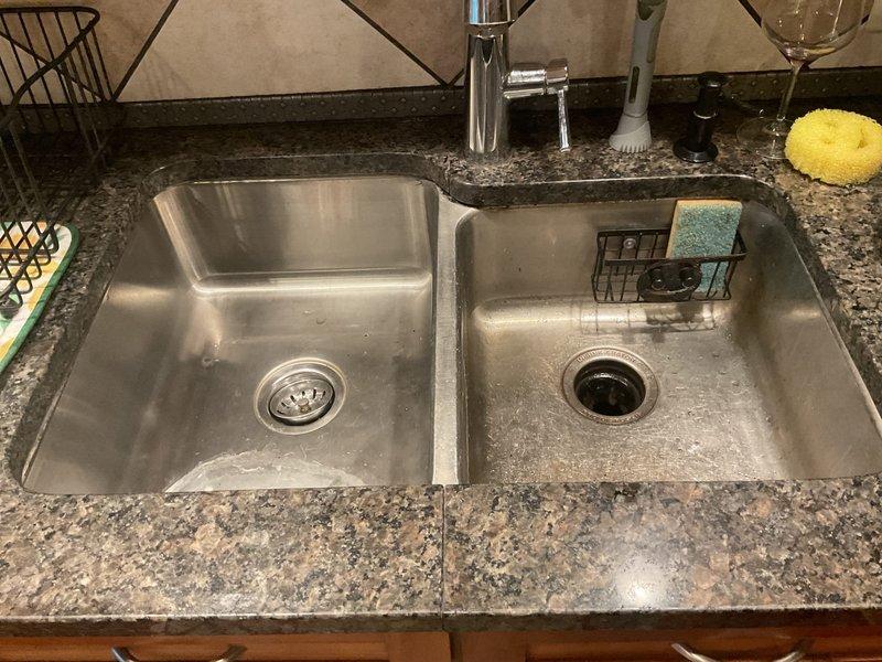 Responded to non-functional garbage disposal at kitchen sink in 20-year-old home. Upon arrival, inspected InSinkErator Pro SS disposal unit mounted beneath double-basin stainless steel sink. Tested unit for power and mechanical function, identified issue preventing operation. Reset disposal using bottom-mounted reset button and verified electrical connection at power outlet in cabinet. Cleared minor obstruction from disposal chamber and confirmed grinding mechanism operated freely. Tested unit under running water to verify full functionality restored. Disposal now operating normally with proper drainage in both sink basins.