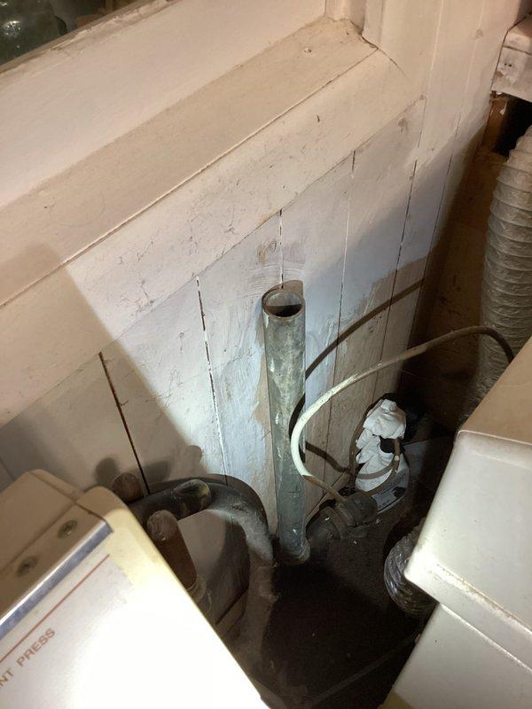 Responded to laundry room washer drain overflow that had been occurring for several weeks. Upon arrival, inspected the drainage system and plumbing infrastructure. Observed aged galvanized piping with significant corrosion, oxidation, and rust-colored mineral deposits on vertical drain lines. Snaked the washer drain line to clear the blockage causing the overflow condition. Verified proper drainage flow after clearing obstruction. Documented existing plumbing conditions showing deteriorated galvanized pipes with visible patina and corrosion throughout the drainage assembly. Issue resolved with drain now flowing freely without backup into laundry room.
