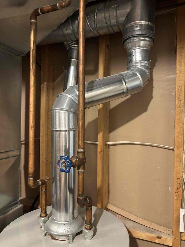 Responded to water heater leak complaint on 12-year-old Bradford unit. Upon inspection, confirmed active leaking from bottom of tank, indicating internal tank failure typical of units in this age range. Documented existing installation with photographs showing water heater, associated copper supply lines, blue-handled shutoff valve, and connected HVAC ductwork in unfinished basement utility area. Advised customer that bottom leaks from water heater tanks are not repairable and require complete unit replacement due to compromised tank integrity.