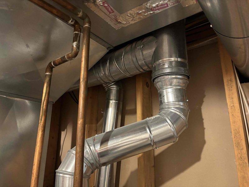 Responded to water heater leak complaint on 12-year-old Bradford unit. Upon inspection, confirmed active leaking from bottom of tank, indicating internal tank failure typical of units in this age range. Documented existing installation with photographs showing water heater, associated copper supply lines, blue-handled shutoff valve, and connected HVAC ductwork in unfinished basement utility area. Advised customer that bottom leaks from water heater tanks are not repairable and require complete unit replacement due to compromised tank integrity.