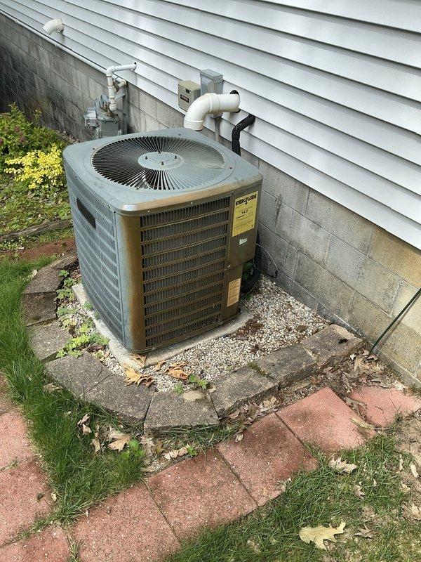 Completed comprehensive AC tune-up service on a 14-year-old residential air conditioning system. Performed standard maintenance procedures including inspection of the outdoor condenser unit, verification of electrical connections at the disconnect box and junction box, and assessment of refrigerant lines and PVC condensate drainage system. Unit found to be in functional condition with normal outdoor weathering present on equipment and concrete pad. Documentation captured showing proper installation configuration with appropriate clearances and component accessibility for future service needs.
