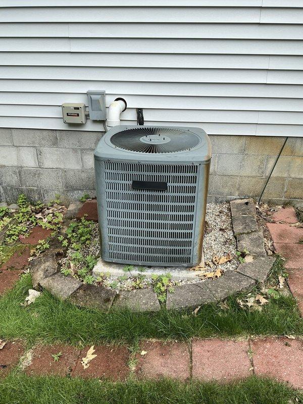 Completed comprehensive AC tune-up service on a 14-year-old residential air conditioning system. Performed standard maintenance procedures including inspection of the outdoor condenser unit, verification of electrical connections at the disconnect box and junction box, and assessment of refrigerant lines and PVC condensate drainage system. Unit found to be in functional condition with normal outdoor weathering present on equipment and concrete pad. Documentation captured showing proper installation configuration with appropriate clearances and component accessibility for future service needs.