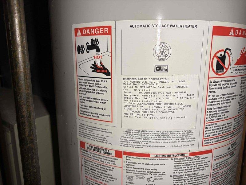 Completed estimate for water heater replacement at customer's request. Inspected existing Bradford White automatic storage water heater, documented unit specifications and current installation configuration including connected piping, venting, and proximity to HVAC equipment in mechanical room. Photographed water heater labels showing model information, safety warnings, and manufacturing details, as well as surrounding utility space with ductwork, insulated pipes, and copper plumbing connections to assess replacement requirements and clearances.