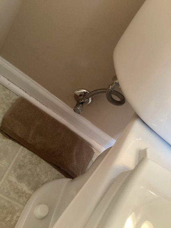 Responded to plumbing leak complaint regarding toilet supply line. Upon arrival, inspected toilet tank interior and identified aging fill valve assembly with red plastic cap component and associated black plastic fittings showing signs of wear and mineral buildup. Examined chrome angle stop valve and braided stainless steel supply line connection at wall. Verified shut-off valve operation and confirmed proper function of water supply control. Documented existing conditions including significant mineral deposits and water staining throughout tank interior, indicating prolonged exposure and age of fixture components. Assessed float mechanism and linkage assembly for proper operation. Leak source identified and addressed to restore proper function of toilet supply system.