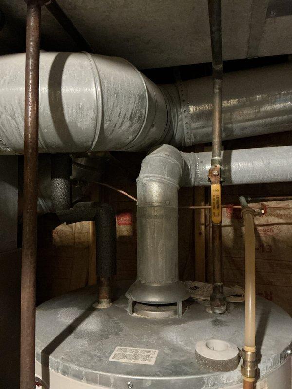 Responded to no hot water complaint and discovered small leak from pipe connection at top of Bradford White water heater. Assessed age and overall condition of unit during inspection. Documented existing plumbing configuration, vent piping, and mechanical room layout with photos for service records.