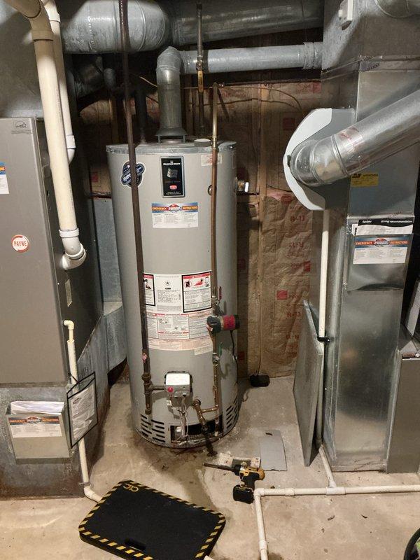 Responded to no hot water complaint and discovered small leak from pipe connection at top of Bradford White water heater. Assessed age and overall condition of unit during inspection. Documented existing plumbing configuration, vent piping, and mechanical room layout with photos for service records.
