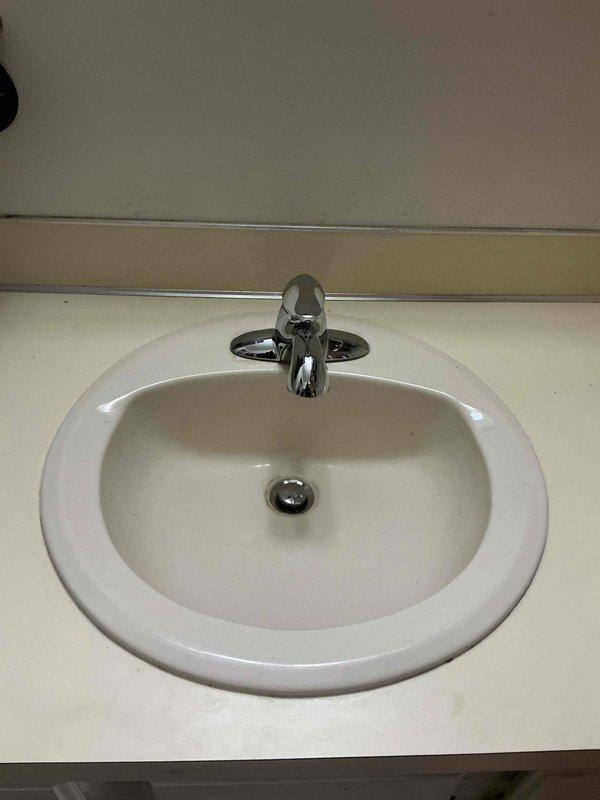 Completed faucet replacement on bathroom vanity sink, removing existing worn fixture and installing new chrome single-handle faucet with dual side handles. Verified proper drainage through P-trap assembly, tested water supply connections for leaks, and confirmed full functionality of new faucet and drain stopper mechanism.