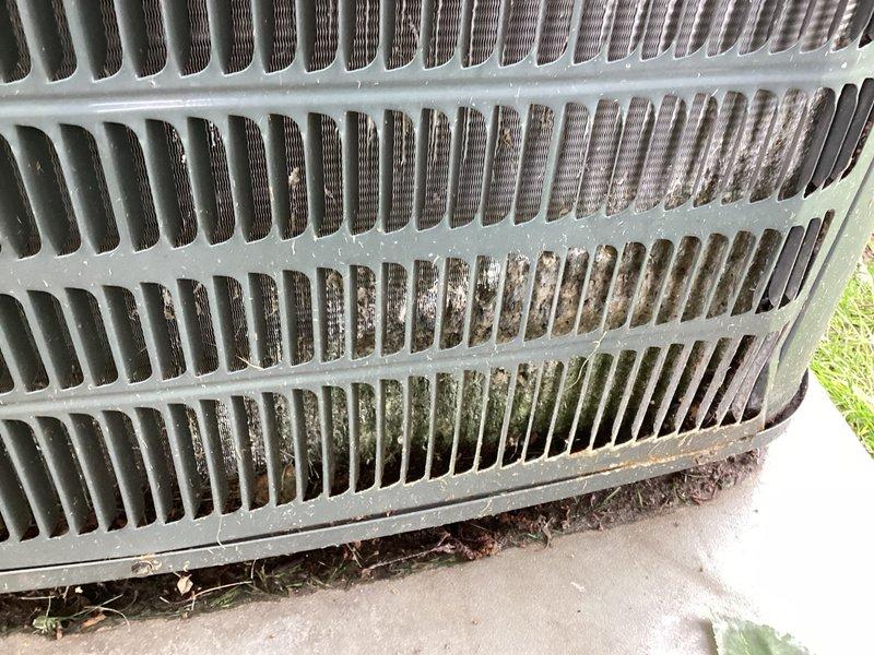 Completed annual cooling maintenance on 14-year-old Goodman air conditioning system with condenser motor replaced in 2022. Performed comprehensive tune-up inspection including visual assessment of outdoor condenser unit, which revealed significant accumulation of dirt, dust, and organic debris throughout the heat exchanger fins and coil surfaces. Documented heavy environmental soiling with brown discoloration and grime buildup, particularly in center and lower sections of the condenser coil, along with leaves and plant matter collected at the base where unit meets concrete pad. System operational and ready for cooling season.