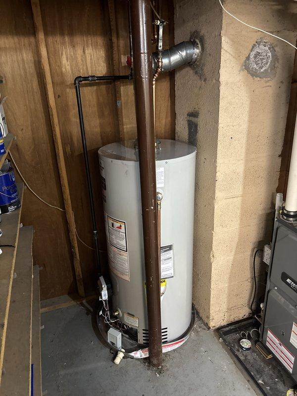 Successfully completed full replacement of air conditioning system and water heater unit. Removed existing equipment and installed new Bradford White automatic storage water heater with natural gas configuration. Unit installed in basement mechanical room against concrete block wall with proper clearances maintained. Connected copper supply and discharge piping with appropriate fittings and joints. Installed metallic exhaust flue with elbow configuration venting through ceiling per code requirements. Pressure relief valve and all safety devices properly installed and tested. All gas connections completed and leak-tested. System filled, purged, and verified for proper operation. Customer requested equipment change to Carrier option during installation, which was accommodated and completed successfully.