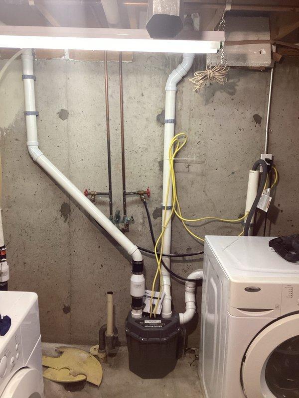 Completed installation of washer pump box system in basement utility area. Installed new white PVC drainage piping with proper vertical and horizontal runs, including necessary elbow joints and wall-mounted brackets for secure attachment to concrete foundation walls. Connected drainage system to black sump pump basin, ensuring proper flow and discharge capabilities. Routed electrical supply using appropriate wiring to power pump system. All plumbing connections tested and verified for proper operation and leak-free performance.