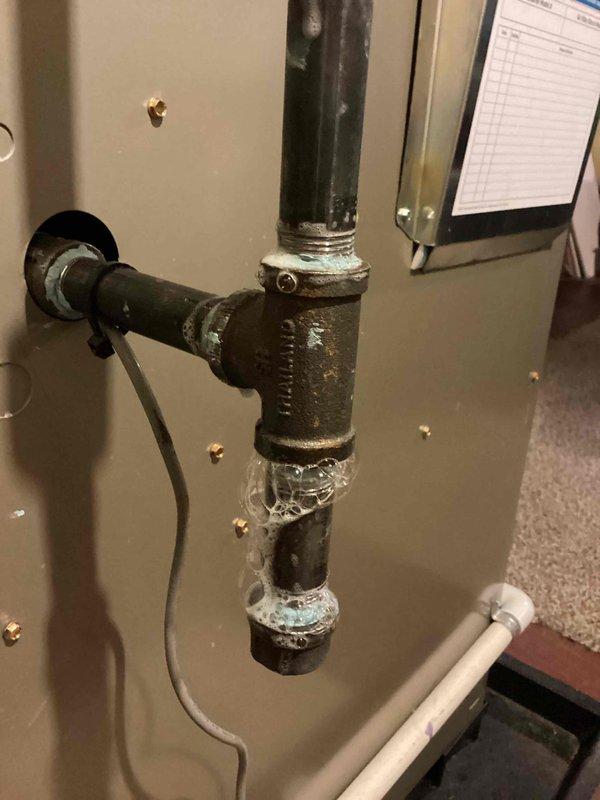 Responded to gas odor complaint near furnace and bathroom area. Performed comprehensive gas leak inspection of recently installed Carrier heating system, including areas not previously checked. Inspected gas piping connections, valves, and fittings throughout the system. Identified corroded gas piping with visible rust and deterioration at threaded connections and joints. Documented conditions with photographs showing significant corrosion on metal gas lines and fittings. System remained operational during inspection with heating function intact. Verified all accessible gas connections for proper sealing and potential leak points, with particular attention to valve connections and aged piping components requiring monitoring or replacement.