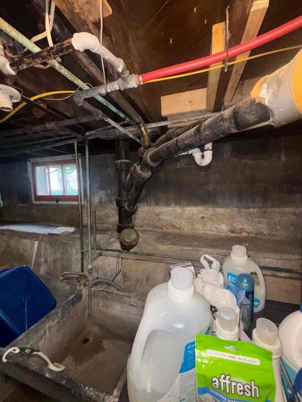Responded to plumbing leak originating from dishwasher supply line in basement utility area. Upon inspection, identified active leak at connection point requiring immediate attention to prevent further water damage to concrete foundation and surrounding infrastructure. Assessed existing plumbing system consisting of mixed-age materials including newer red PEX piping, white PVC, and older corroded steel pipes running through exposed ceiling joists. Secured leak source, completed necessary repairs to dishwasher supply line connection, and verified system integrity with pressure test to ensure no additional leaks present in the immediate plumbing network.