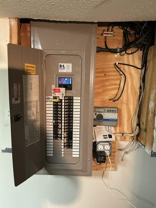 Completed comprehensive Electrical Club Inspection for 2021 construction. Documented exterior utility installation including meter base, service entrance conduit, and associated electrical components mounted on residential siding. Inspected and photographed interior main electrical panel with digital monitoring system, verified proper circuit breaker arrangement and labeling, and documented auxiliary electrical components including surge protection devices and control systems mounted on exposed framing in utility area.