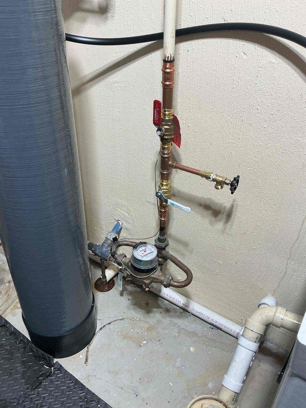 Completed replacement of ball valves on exterior water supply system in coordination with city water shutdown. Installed new red-handled ball valve and associated brass fittings on vertical copper pipe assembly, ensuring proper connections to existing plumbing infrastructure including pressure gauge and meter device. All valves tested for proper operation and system restored to full functionality.