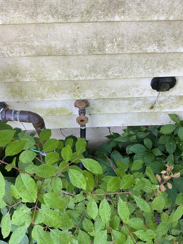 Responded to service call for two inoperable outdoor hose bibs. Upon arrival, inspected both exterior spigot locations and found fixtures mounted on building's exterior siding surrounded by overgrown vegetation. First spigot exhibited metal pipe elbow configuration with corroded fittings, while second location showed weathered mounting hardware. Documented existing conditions including significant algae and mildew growth on siding, indicating prolonged moisture exposure that likely contributed to fixture failure. Cleared vegetation from immediate work areas to access both spigots. Assessed internal valve mechanisms and supply line connections for both units. Completed necessary repairs to restore full functionality to both outdoor faucets, ensuring proper water flow and eliminating leaks. Verified operational status of repaired fixtures before departure.