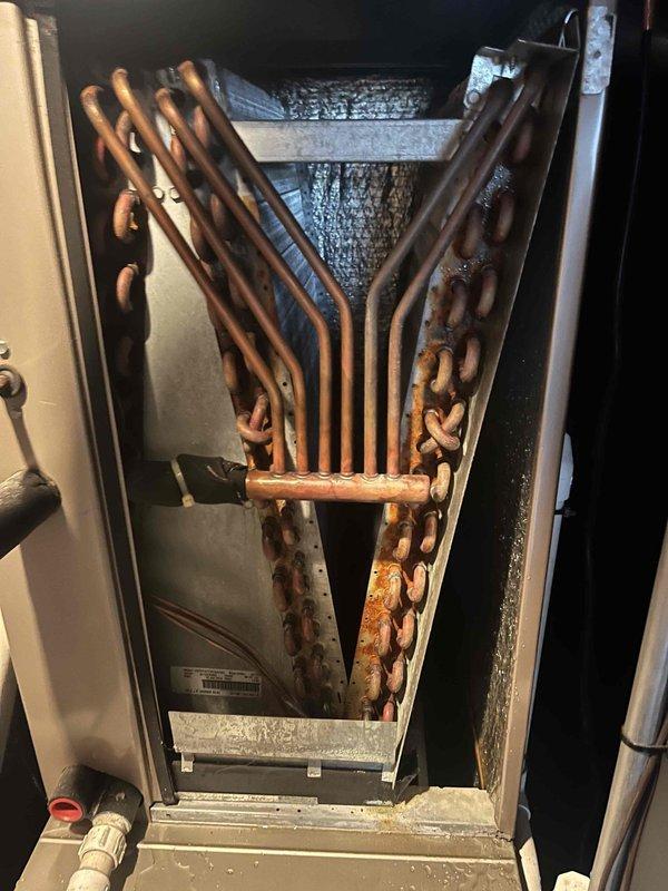 Responded to water leak concern on 9-year-old HVAC system. Upon inspection, discovered significant corrosion and oxidation on evaporator coil assembly with visible rust-colored patina throughout copper tubing. Identified compromised condensate drain system with staining and debris accumulation in PVC drainage piping. Documented condition of heat exchanger coil showing advanced deterioration and assessed condensate pan for proper drainage function. Provided maintenance service and recommendations for system repair to resolve active water leak issue.