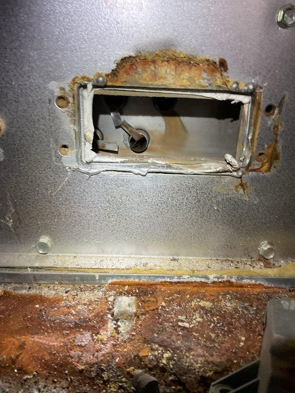 Responded to service call for 20-year-old cooling unit blowing lukewarm air instead of cold air. Upon inspection, accessed interior components through existing service panels and documented significant corrosion and rust around access points and metal surfaces, indicating age-related deterioration and possible moisture exposure. Identified compromised insulation material and corroded metal components within the air handling system that may be contributing to reduced cooling efficiency and improper temperature output.