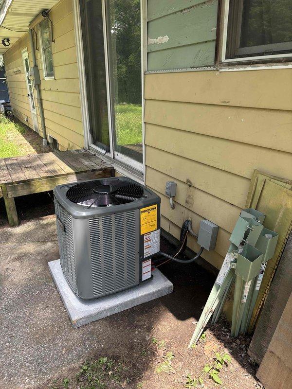Completed full residential air conditioning system replacement at single-family home. Removed existing condensing unit and installed new gray/silver outdoor AC condenser on concrete pad adjacent to yellow vinyl-sided exterior. Properly mounted electrical disconnect box on exterior wall, ran refrigerant lines and electrical conduit through siding penetration, and secured all connections per manufacturer specifications. Verified unit placement on level concrete pad, tested system operation, and confirmed all warning labels and specifications were clearly visible on equipment. Installation completed as same-day service with all components functioning properly upon final inspection.