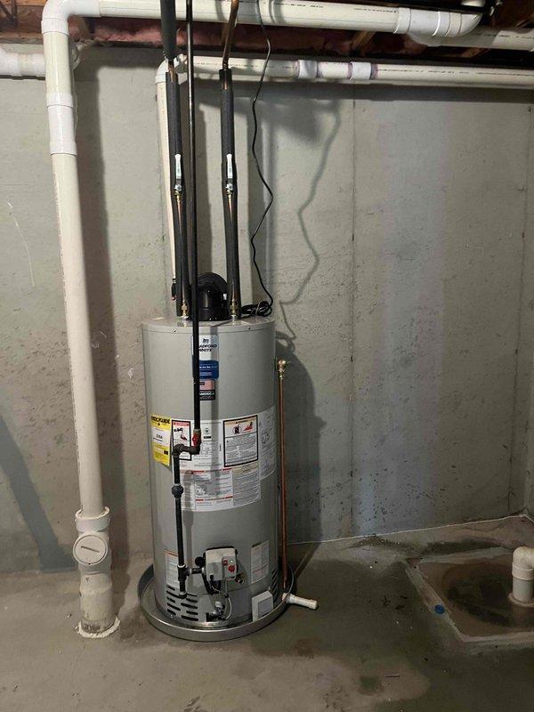 Completed installation of 50-gallon power vent water heater in basement utility area. Unit was positioned against concrete block wall with proper clearances, connected to existing water supply lines with copper piping and foam insulation sleeves, and integrated with PVC power vent exhaust system. All electrical connections, safety controls, and recirculation pump were installed and tested for proper operation.