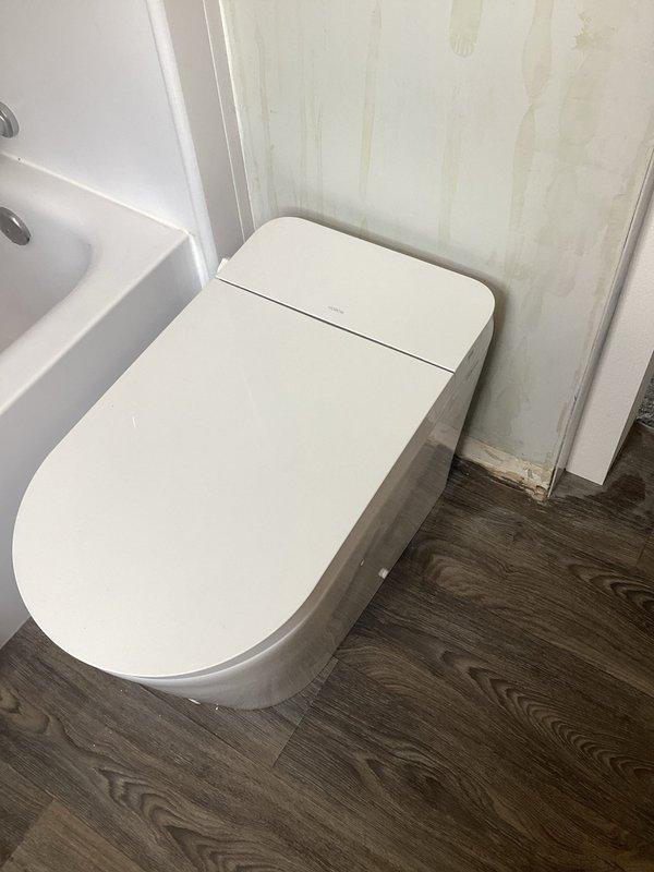 Relocated toilet water supply line to accommodate proper toilet positioning and replaced worn toilet flange to ensure secure mounting and prevent future leaks. Adjusted flange height to align flush with new flooring surface, completing installation with proper sealing to maintain watertight integrity.