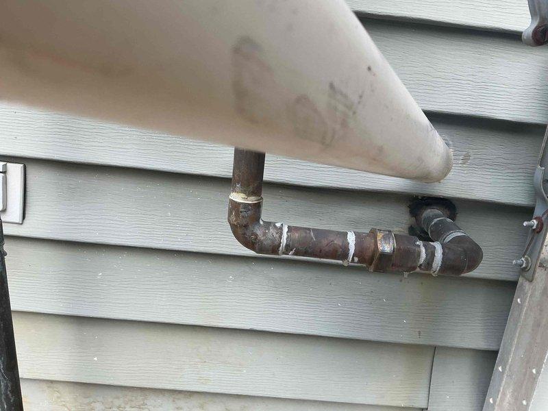 Conducted plumbing project estimate for property with dual water treatment systems—existing water softener and Gordon water system. Evaluated feasibility of removing one system to optimize space and assessed requirements for installing new laundry room sink. Documented exterior plumbing infrastructure including corroded copper piping with temporary patch repairs, exterior-mounted pressure regulation equipment, and ground-level utility connections with PVC drainage lines. Photographed existing conditions to provide comprehensive assessment for system consolidation and laundry room addition.