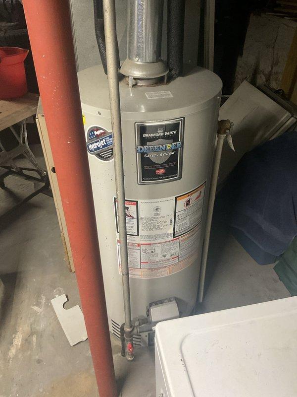 Conducted on-site evaluation of 15-year-old Bradford White Defender Safety System water heater for replacement estimate. Documented existing unit specifications, plumbing connections including top-mounted metal and PVC piping configurations, bottom gray PVC connections with shutoff valves, and venting system to provide accurate replacement recommendations and scope of work.
