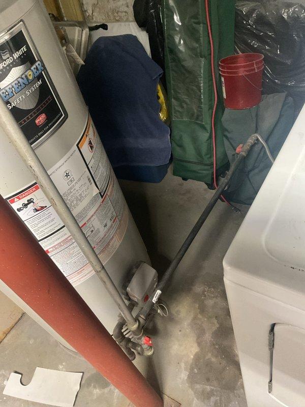 Conducted on-site evaluation of 15-year-old Bradford White Defender Safety System water heater for replacement estimate. Documented existing unit specifications, plumbing connections including top-mounted metal and PVC piping configurations, bottom gray PVC connections with shutoff valves, and venting system to provide accurate replacement recommendations and scope of work.