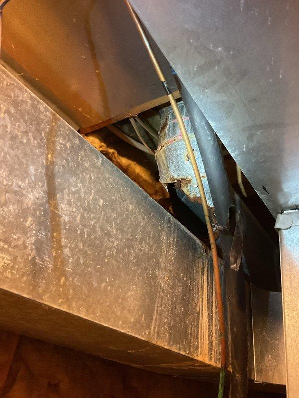 Responded to service call for non-operational 26-year-old Comfortmaker air conditioning unit suspected of requiring R22 refrigerant recharge. Upon inspection, documented significant deterioration of attic ductwork including severely compromised insulation wrapping, extensive rust corrosion on exposed metal surfaces, and structural integrity concerns with visible gaps and openings in damaged sections. Prepared estimate for system repair considerations prior to scheduled replacement installation.