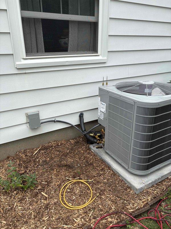 Completed full HVAC system installation including new furnace and air conditioning condenser unit. Installed outdoor condenser on concrete pad with proper refrigerant line connections, electrical disconnect box, and insulated line set penetrating exterior wall. All equipment positioned per manufacturer specifications, refrigerant lines properly secured and insulated, electrical connections completed and verified operational.