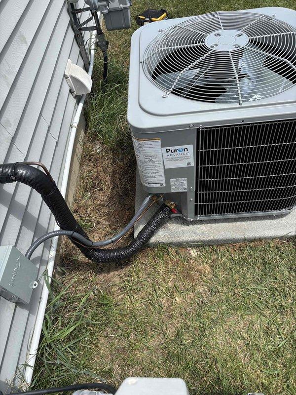 Completed full installation of residential HVAC system including new furnace and air conditioning unit. Installed outdoor condenser unit on concrete pad with proper electrical connections via black flexible conduit and disconnect box. Unit utilizes R-410A Puron refrigerant system. All electrical components properly mounted to building exterior including service disconnect and metering connections. System installed per manufacturer specifications with appropriate clearances and access points. All required documentation processed and identification verification completed for financing approval. Installation tested and operational.