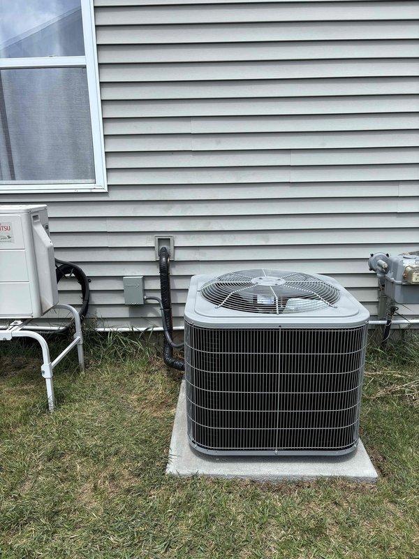 Completed full installation of residential HVAC system including new furnace and air conditioning unit. Installed outdoor condenser unit on concrete pad with proper electrical connections via black flexible conduit and disconnect box. Unit utilizes R-410A Puron refrigerant system. All electrical components properly mounted to building exterior including service disconnect and metering connections. System installed per manufacturer specifications with appropriate clearances and access points. All required documentation processed and identification verification completed for financing approval. Installation tested and operational.