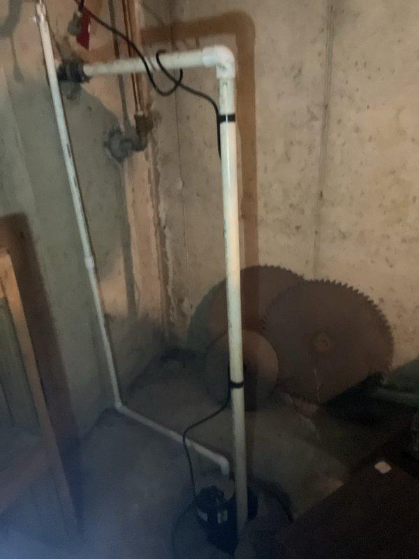 Responded to sump pump failure in basement utility area. Removed existing non-functional sump pump unit and assessed drainage system configuration. Installed new sump pump with appropriate discharge capacity for residential application. Reconfigured plumbing connections including vertical PVC discharge piping to ensure proper drainage flow and code compliance. Installed new basin cover/lid to seal basement floor opening, preventing debris entry and reducing moisture exposure. Secured all piping with appropriate fasteners and verified electrical connections for pump operation. Tested system operation and confirmed proper cycling and discharge functionality.