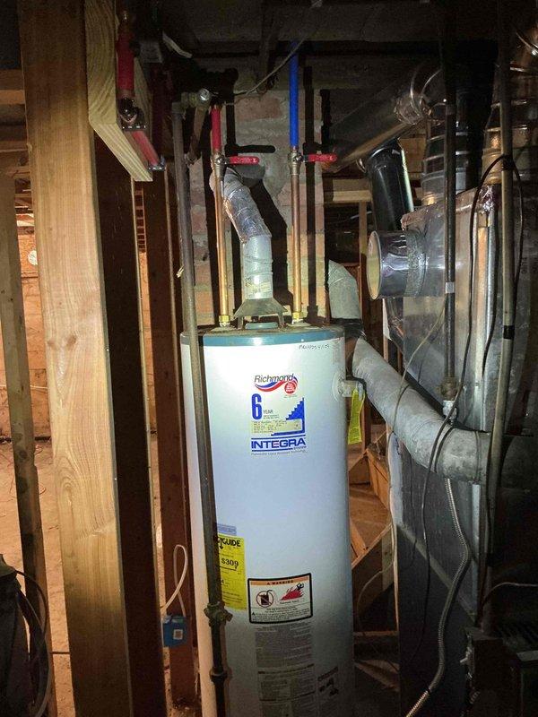 Responded to service call for tankless water heater installation. Upon arrival, found customer had purchased new tankless unit requiring professional installation. However, assessment revealed existing Richmond Integra conventional tank water heater already installed in unfinished basement utility area with all plumbing connections, venting, and shut-off valves properly configured and operational. Consulted with customer regarding discrepancy between service request for tankless installation and current conventional tank system in place. Inspected existing installation including copper supply lines with red-handled valves, PEX connections, and metallic venting system - all components found to be code-compliant and functioning correctly. No tankless water heater installation performed as conventional unit already serving property.