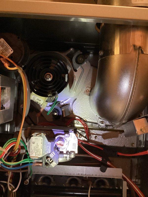 # NC-No Cool Service Call - 14-Year Carrier Unit

Responded to no cooling complaint on 14-year-old Carrier system that was completely non-operational. Upon arrival, performed systematic diagnostic evaluation of the HVAC system to identify failure points.

Opened access panels and inspected interior components including control board, wiring harnesses, and electrical connections. Documented existing conditions showing multiple colored wires (red, white, blue, black, brown, green) connecting from control board to various terminals and components throughout the unit. Observed evidence of moisture infiltration in drain pan with visible water staining, discoloration, rust, and mineral deposits indicating previous or ongoing condensate management issues.

Examined blower motor assembly, gas valve controls with purple/blue accenting, heat exchanger with bronze/copper finish, and all associated mounting hardware. Verified proper wire routing and connection integrity across all electrical compo