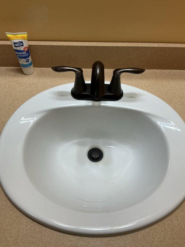 Installed customer-supplied faucet in bathroom sink, replacing existing fixture in 2004-built home. Removed old faucet assembly, installed new two-handle faucet with pop-up drain assembly, tested for proper operation and verified no leaks. Completed installation with photographic documentation showing finished work.